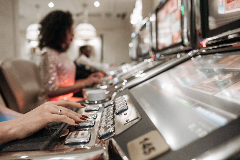 Tangan pemain di depan deretan mesin slot